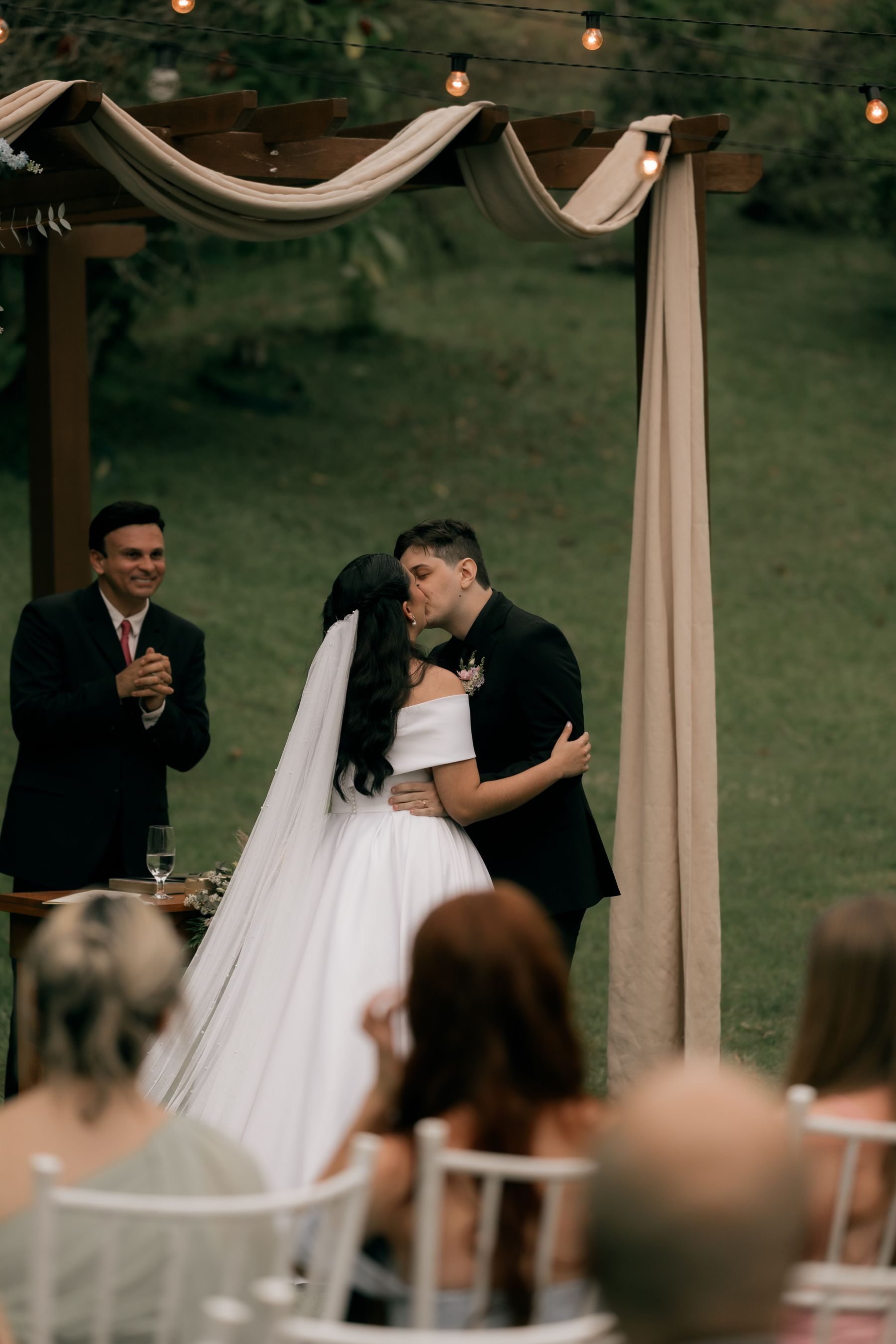A couple sharing a kiss under a floral wedding arch