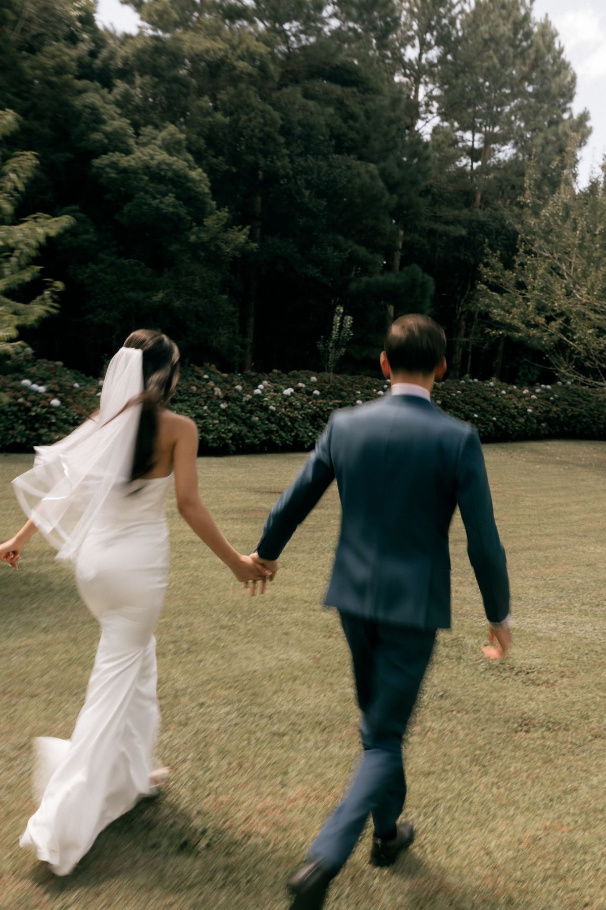 A couple walking hand in hand through a garden