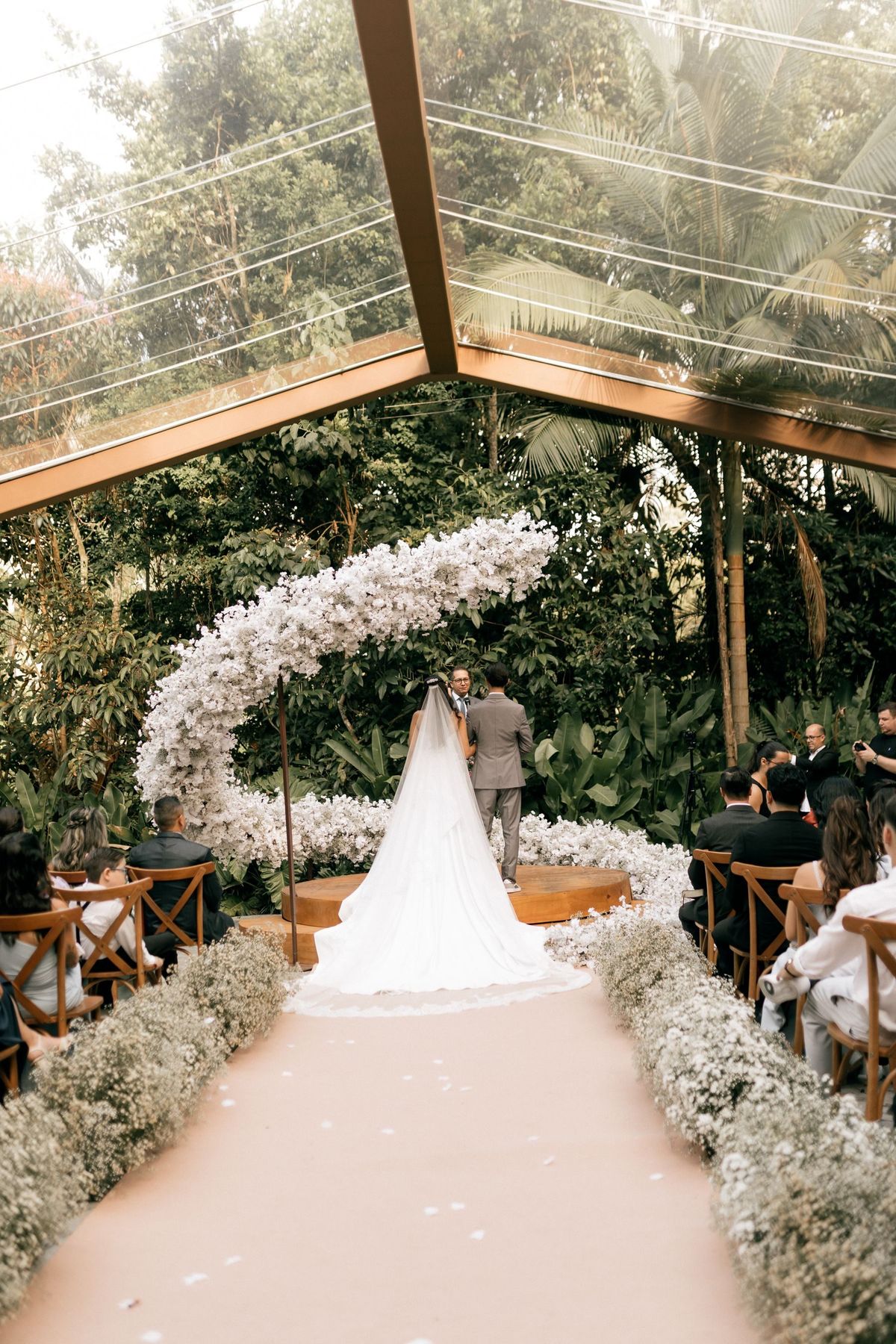 A couple under a glass arch filled with flowers