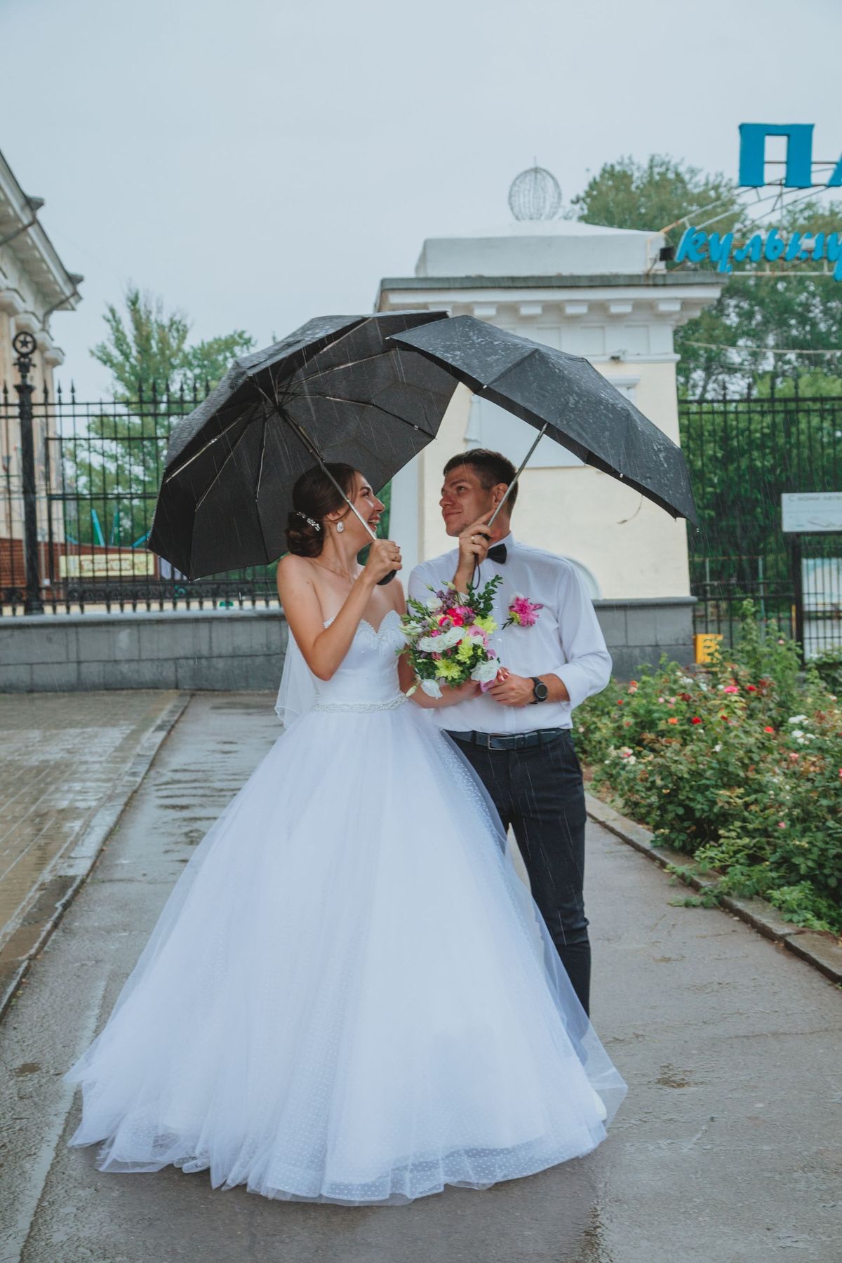 A bride and groom smiling under an umbrella